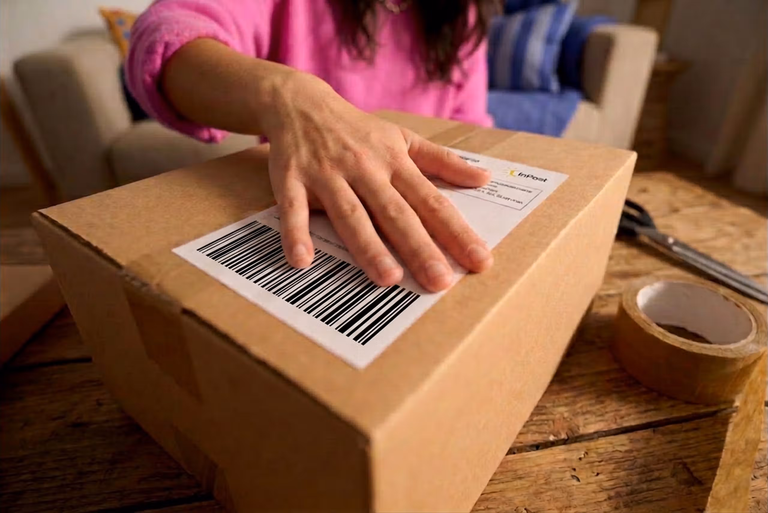 Pessoa a colar uma etiqueta de envio numa caixa para enviá-la com a InPost